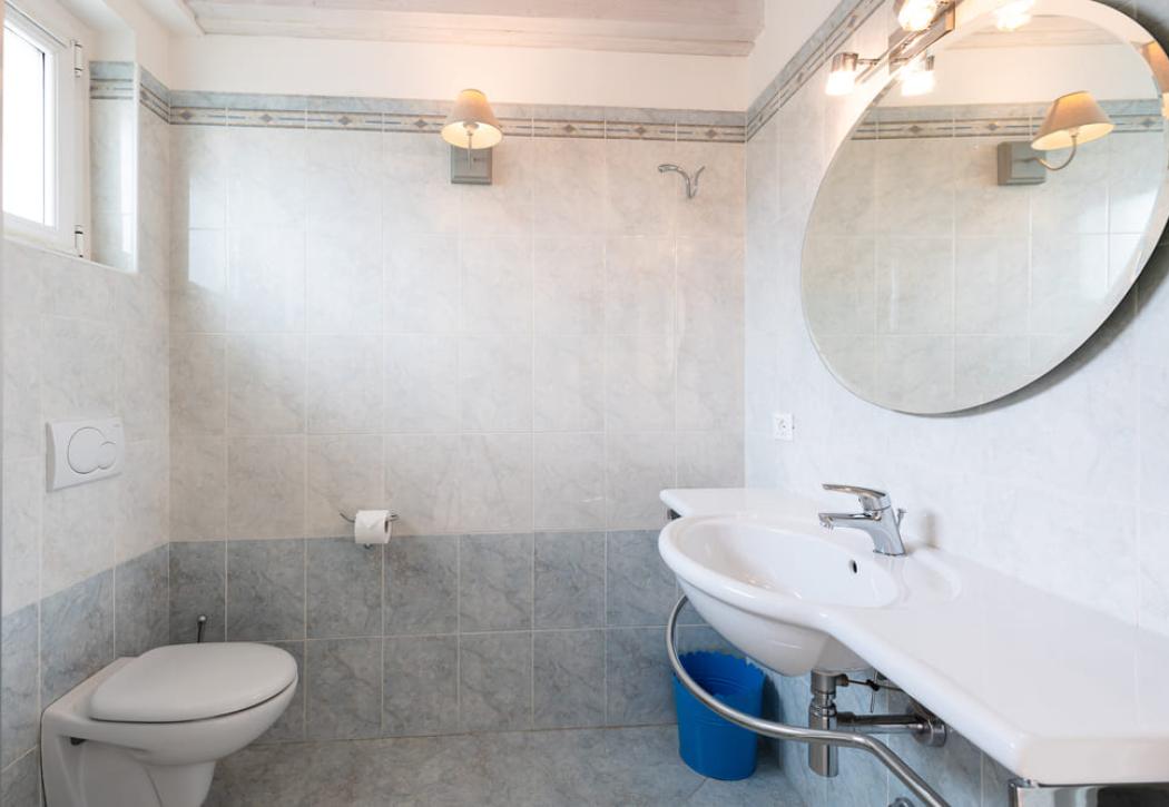 Salle de bain lumineuse avec miroir ovale, lavabo et toilettes.
