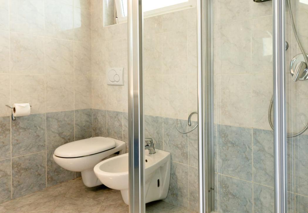 Salle de bain moderne avec douche, bidet et fenêtre ouverte.