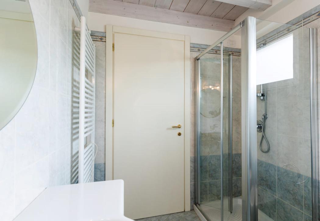 Salle de bain moderne avec douche en verre et porte blanche.
