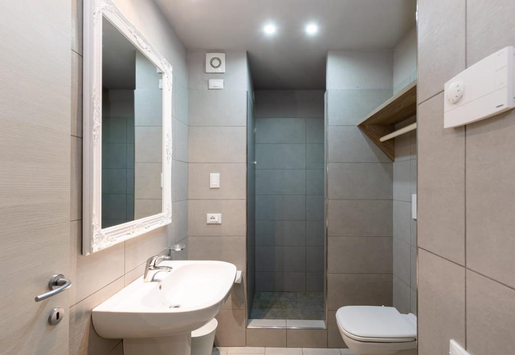 Salle de bain moderne avec douche, miroir décoré et lavabo blanc.