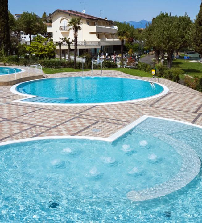 Outdoor pool with circular basins and a garden view.