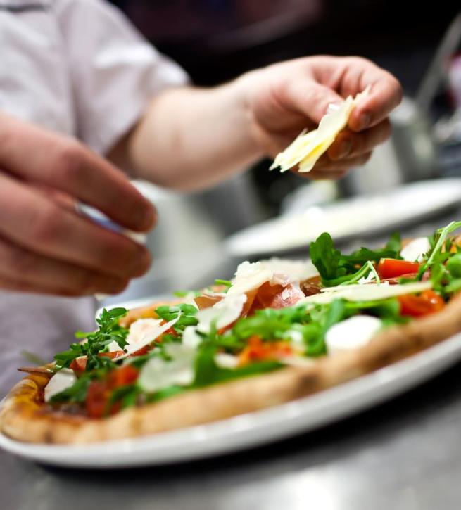 Gourmet pizza with arugula, tomatoes, and cheese shavings.